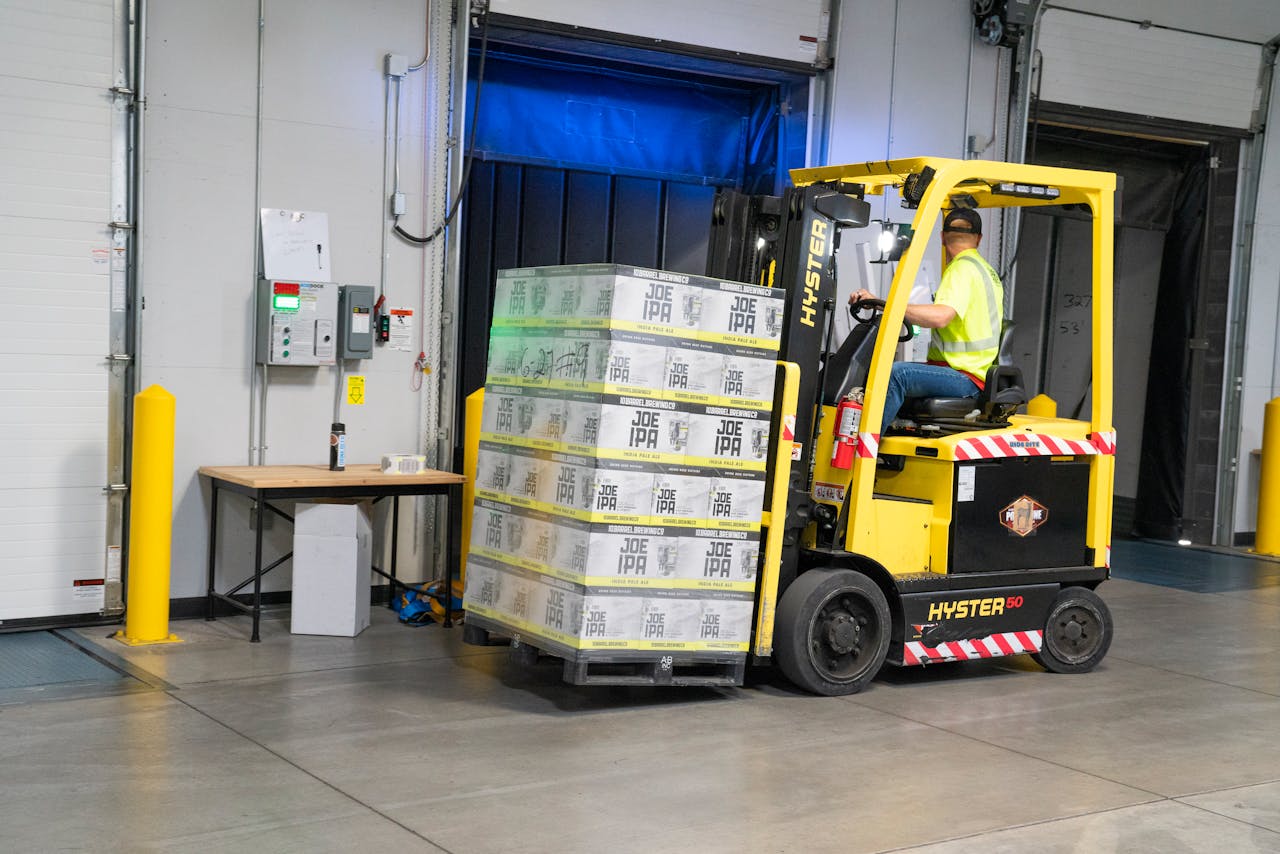 A warehouse employee operating a forklift to move stocked goods indoors. Perfect for industry and logistics visuals.